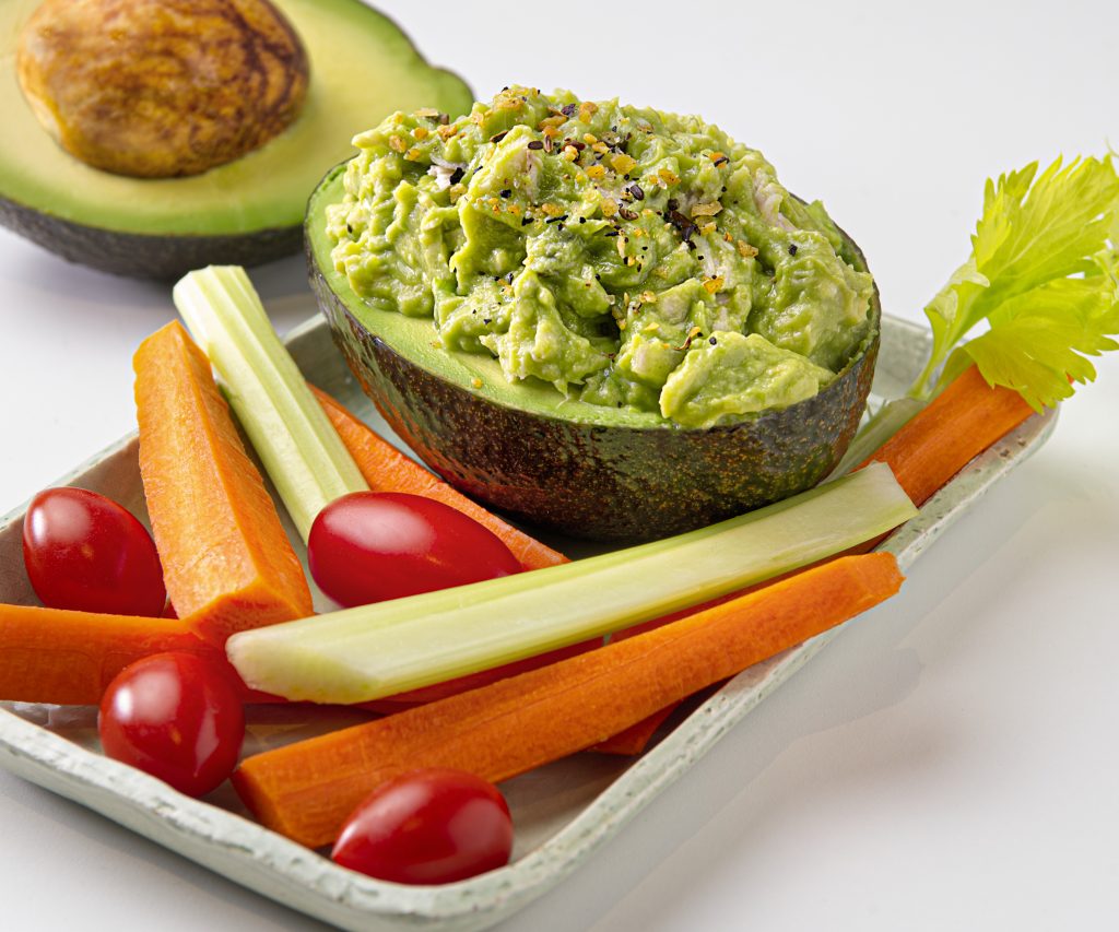 Avocado Chicken Salad in Avo Half with Fresh Veggies on White Plate Avo in Background